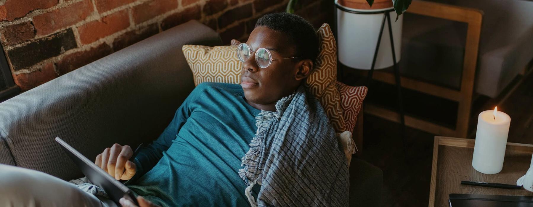 a man looks at his tablet while lying on his living room couch